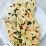 Close up photograph of naan breads covered with oil and herbs