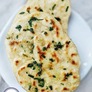 Close up photograph of naan breads covered with oil and herbs