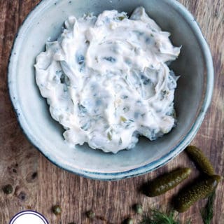 A bowl of tartar sauce on a wooden board