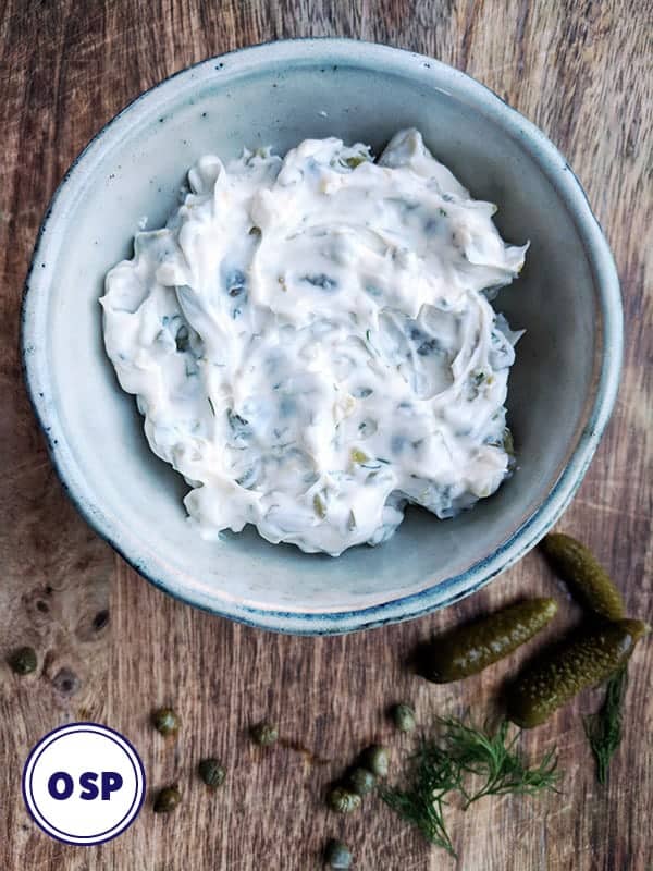A bowl of tartar sauce on a wooden board