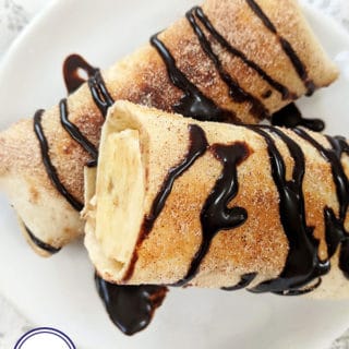 Two banana fritters drizzled with chocolate sauce