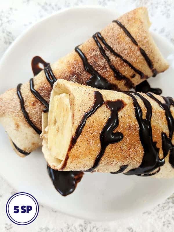 Two banana fritters drizzled with chocolate sauce