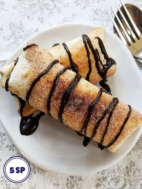 Two banana fritters drizzled with chocolate sauce