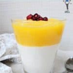 A glass of parfait topped with mango and pomegranate