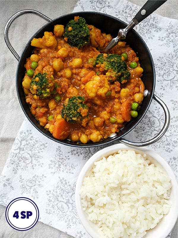 A bowl of chickpea and lentil curry and a bowl of rice