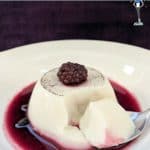 A milk jelly dessert with a red berry coulis in a white dish