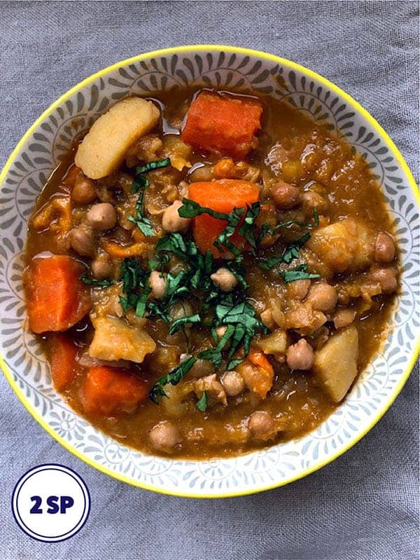 A bowl of vegetable and chickpea broth topped with herbs