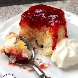 A pear sponge topped with raspberry jam on a white plate