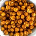 A white bowl full of roasted chickpeas covered in spice