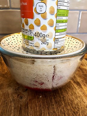 A summer pudding with a can on top to weight it