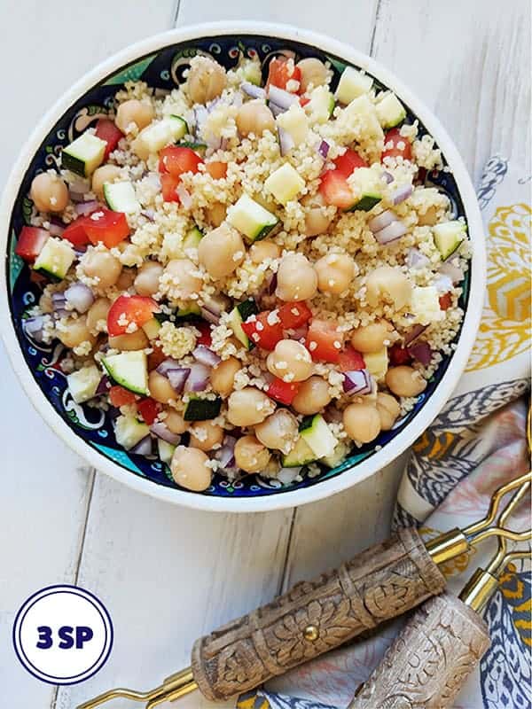 A bowl of couscous salad on a white table