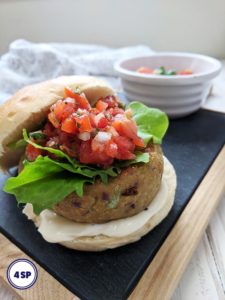 A falafel burger in a bun topped with lettuce & salsa