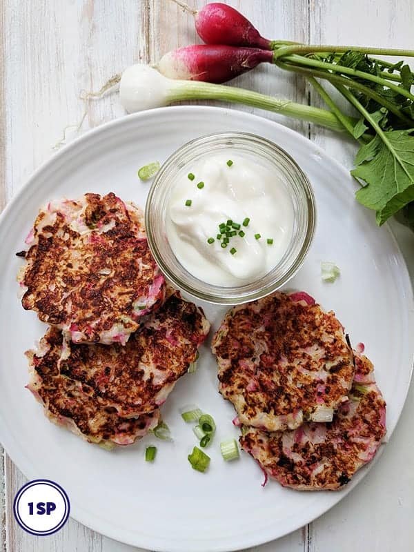 A white plate with 4 radish fritters and a dipping sauce