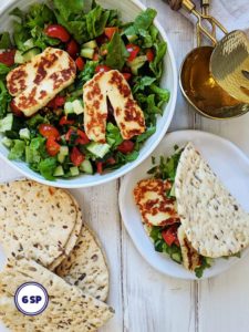 A bowl of salad topped with halloumi cheese