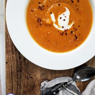 A bowl of butternut squash & red chilli soup in a white bowl