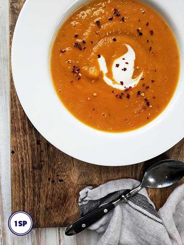 A bowl of butternut squash & red chilli soup in a white bowl