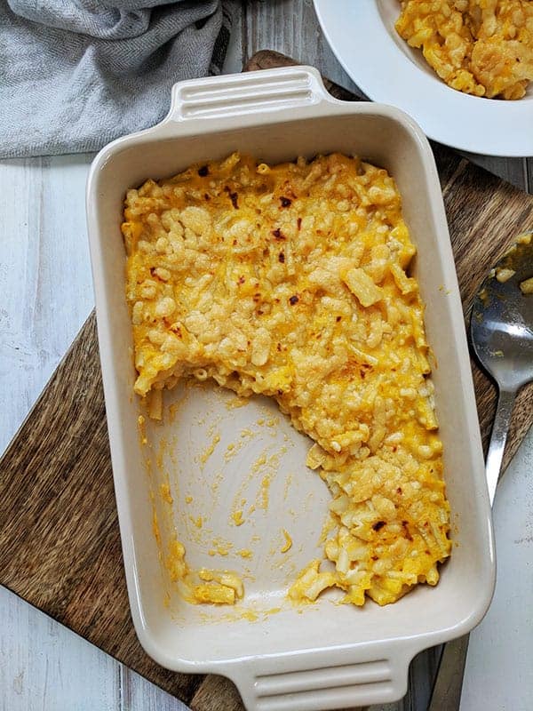 A dish of macaroni cheese on a wooden board