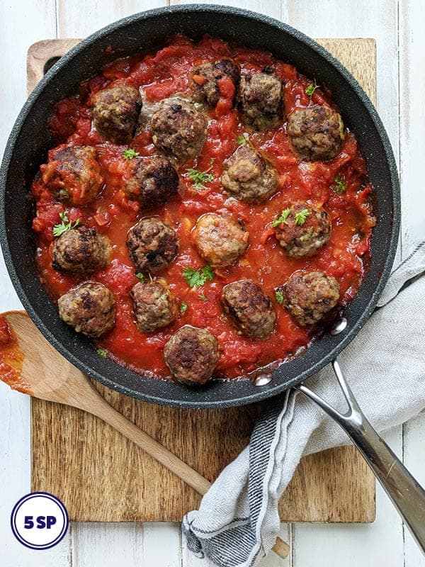 A pan of Italian meatballs on a wooden board