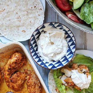 A dish of shawarma chicken with flatbreads and salad