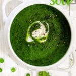 A bowl of spinach and pea soup on a white background