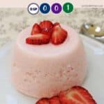 A pink dessert on a white plate with strawberries