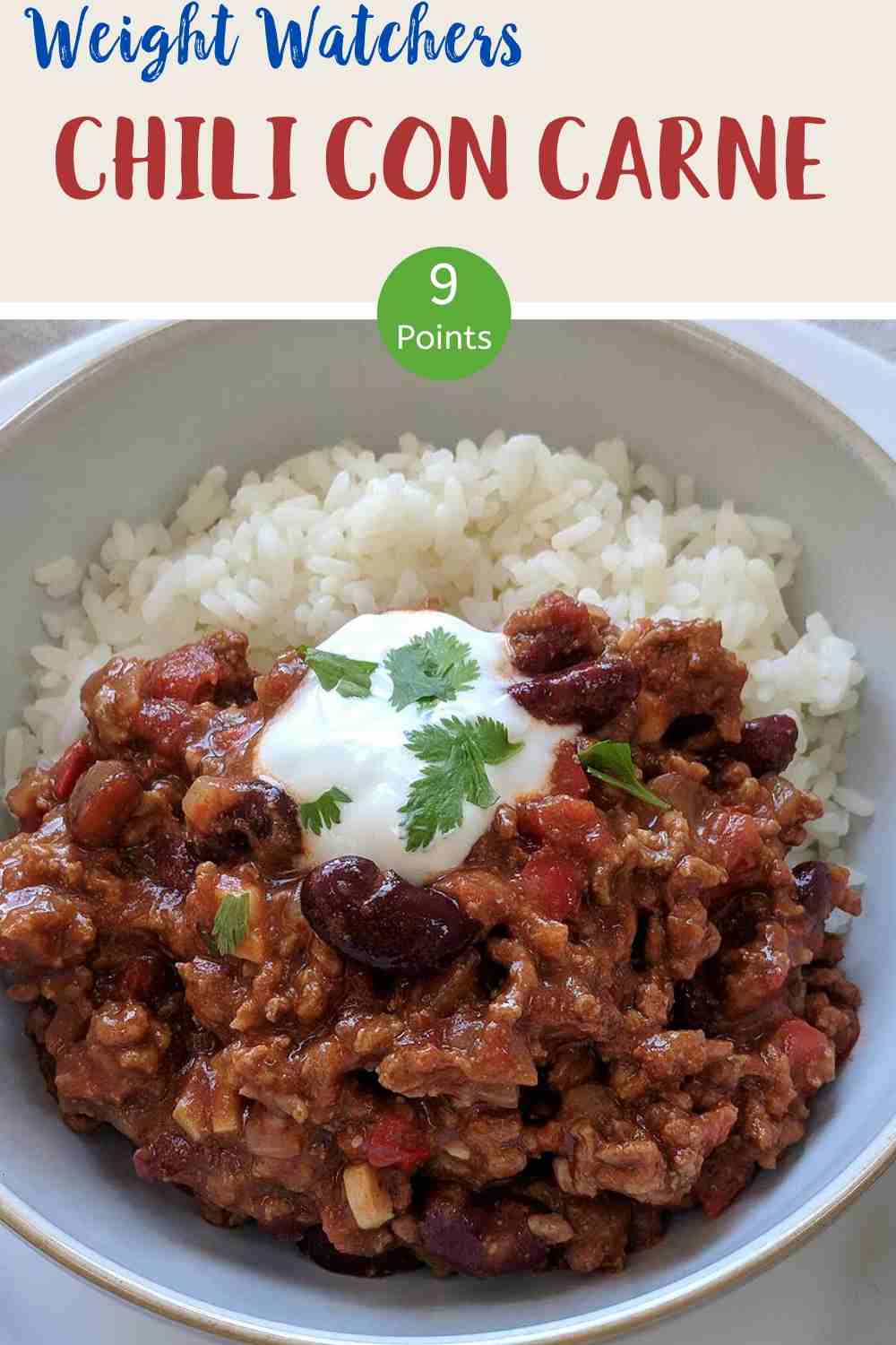 A white bowl filled with chili con carne & rice topped with yogurt and green herbs