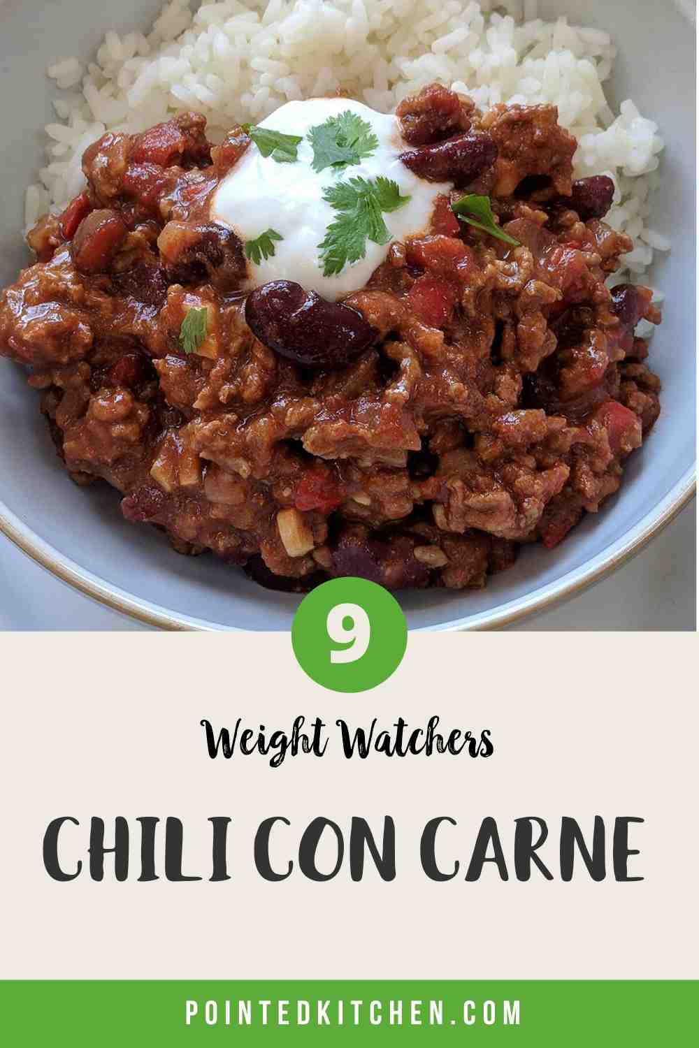 A white bowl filled with chili con carne & rice topped with yogurt and green herbs