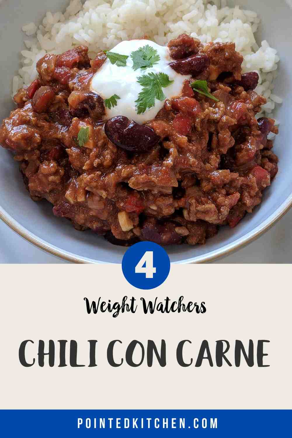 A white bowl filled with chili con carne & rice topped with yogurt and green herbs