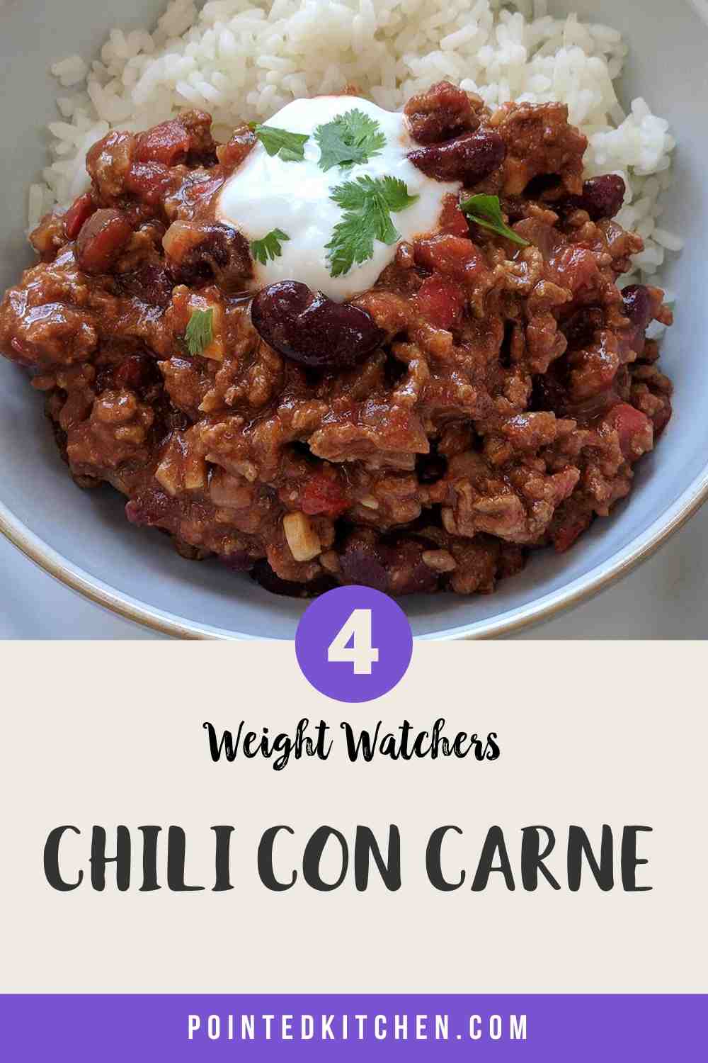 A white bowl filled with chili con carne & rice topped with yogurt and green herbs