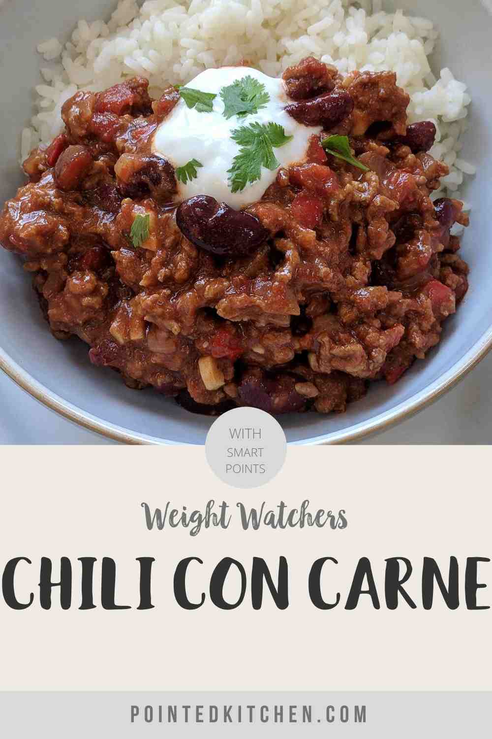 A white bowl filled with chili con carne & rice topped with yogurt and green herbs