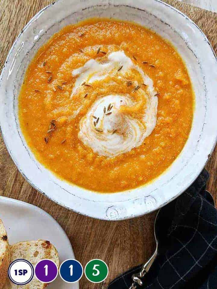 A bowl of carrot and lentil soup in a white bowl.