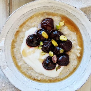 A bowl of porridge with cherries and pistachios