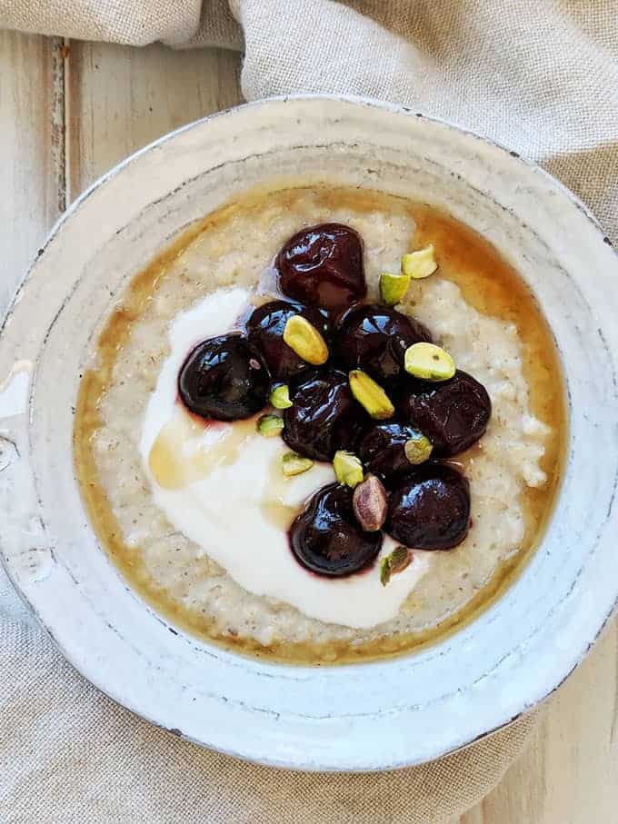 A bowl of porridge with cherries and pistachios