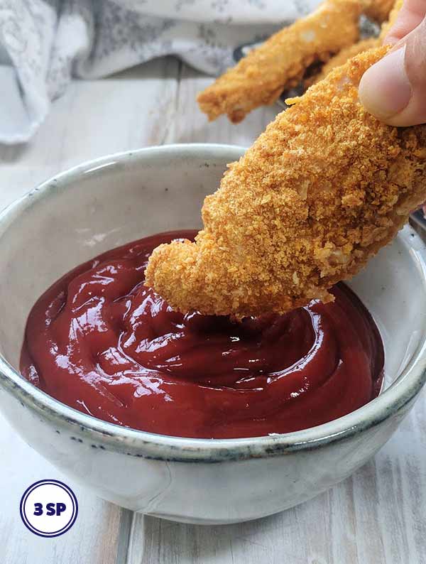 A Chicken tender being dipped into sauce