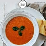 A bowl of tomato soup with some basil