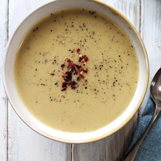 A bowl of Spiced Parsnip Soup on a white table