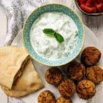 A white plate with falafel, pitta bread and tzatziki