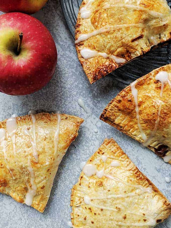 Apple turnovers on a table with a red apple