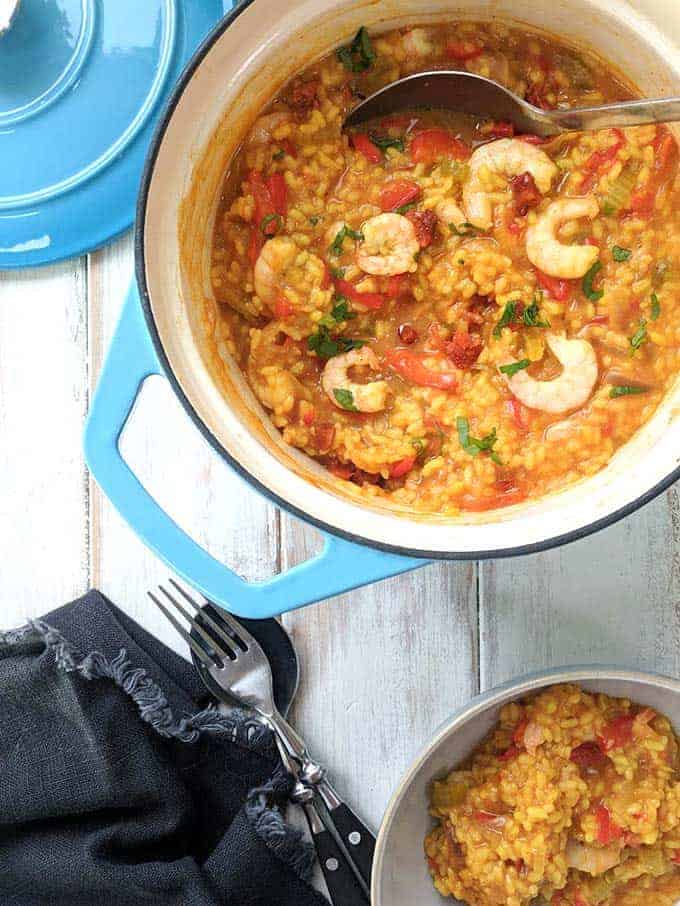 A pot of shrimp, chorizo and red pepper paella on a white table