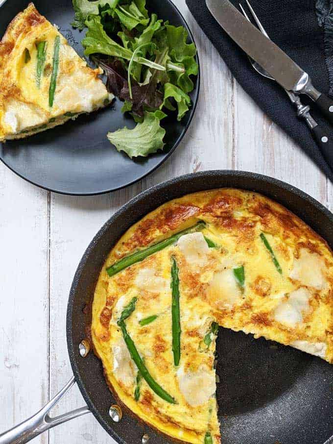 An asparagus and brie frittata with a slice out