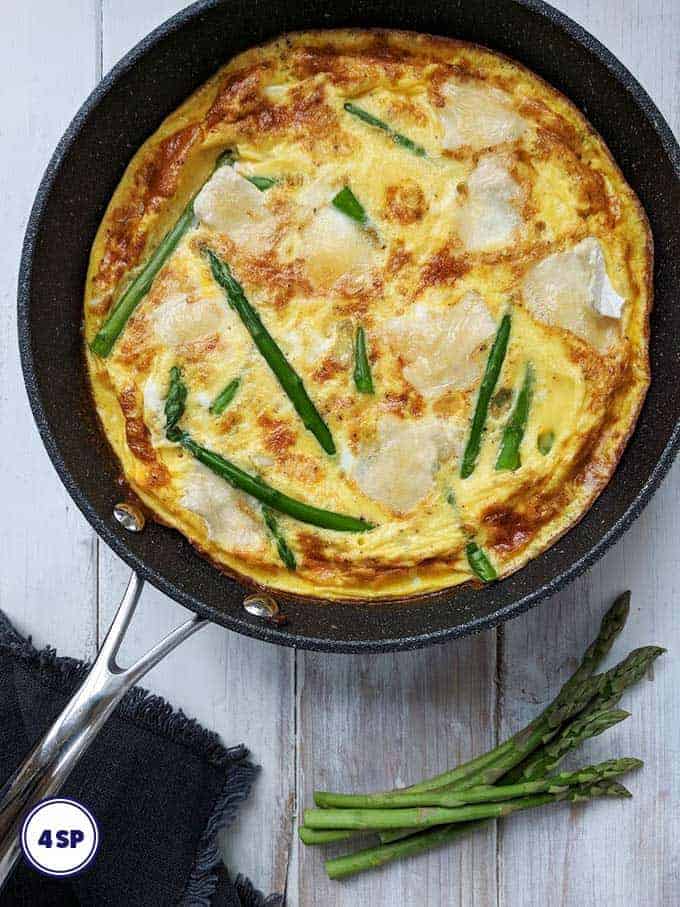 An asparagus and brie frittata on a white table