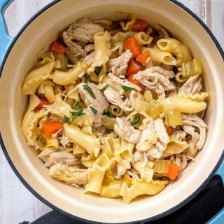 A blue & cream dish of hearty chicken noodle soup
