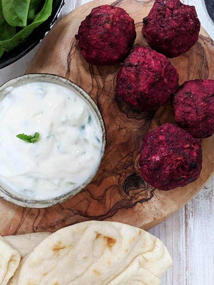 Beetroot falafels on a board with tzatziki