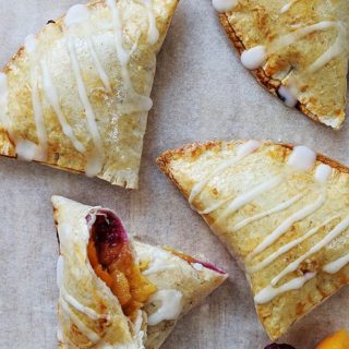 Peach pies on a sheet of baking parchment