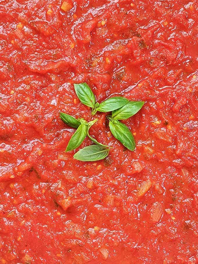 Bright red marinara sauce topped with green basil