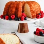 A pineapple angel food cake on a cake stand surrounded by berries