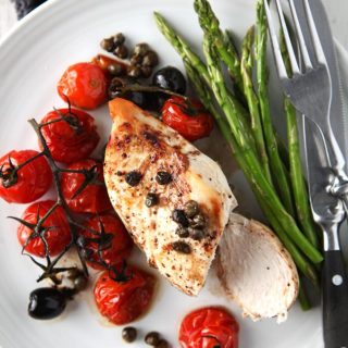 A plate of balsamic chicken on a white plate with asparagus