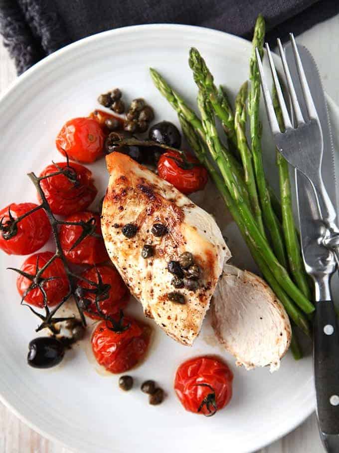 A plate of balsamic chicken on a white plate with asparagus