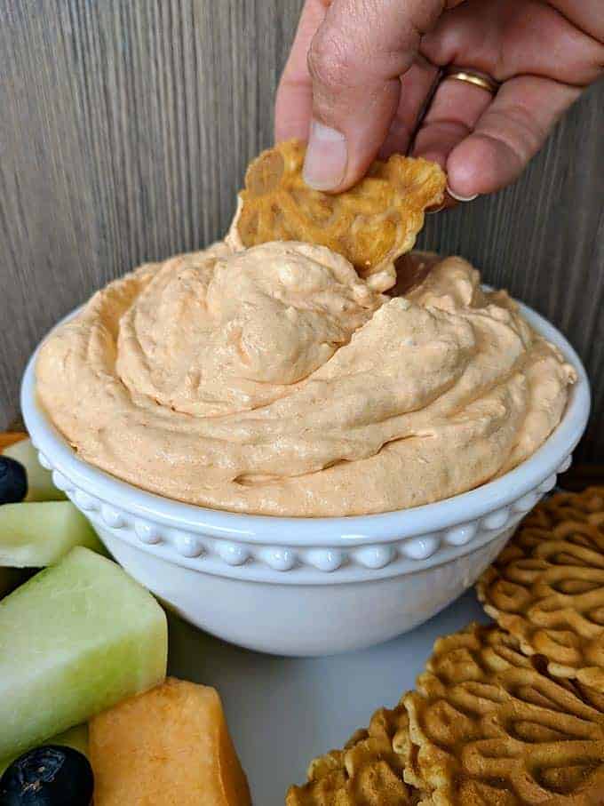 A bowl of pumpkin fluff with a cookie being dipped in