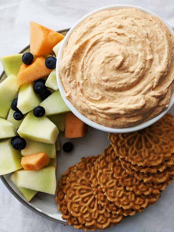 A bowl of pumpkin fluff surrounded by fruit and cookies